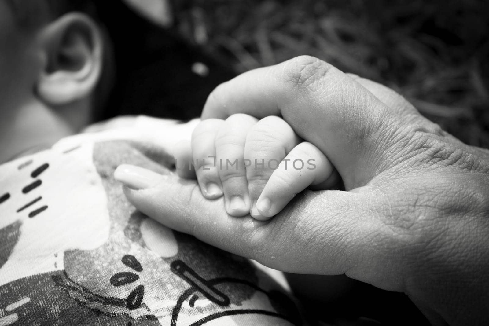 Two month old baby holding his mothers finger. Relax scene