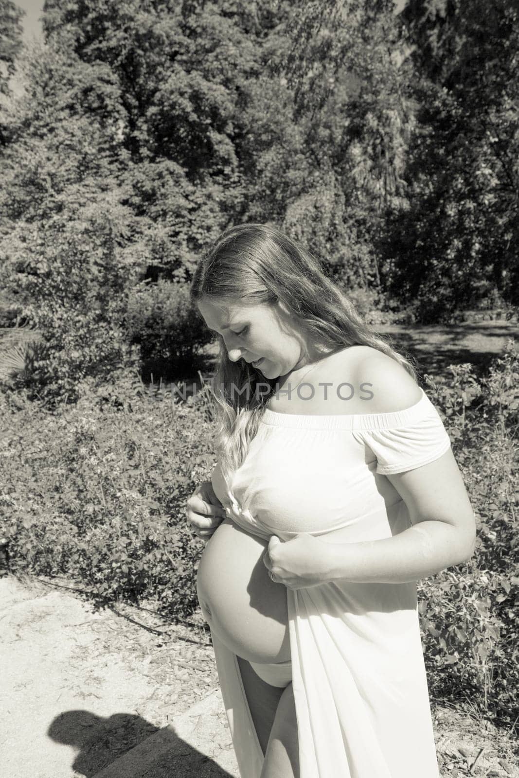 Seven month pregnant woman standing dressed in pink. Happy expression