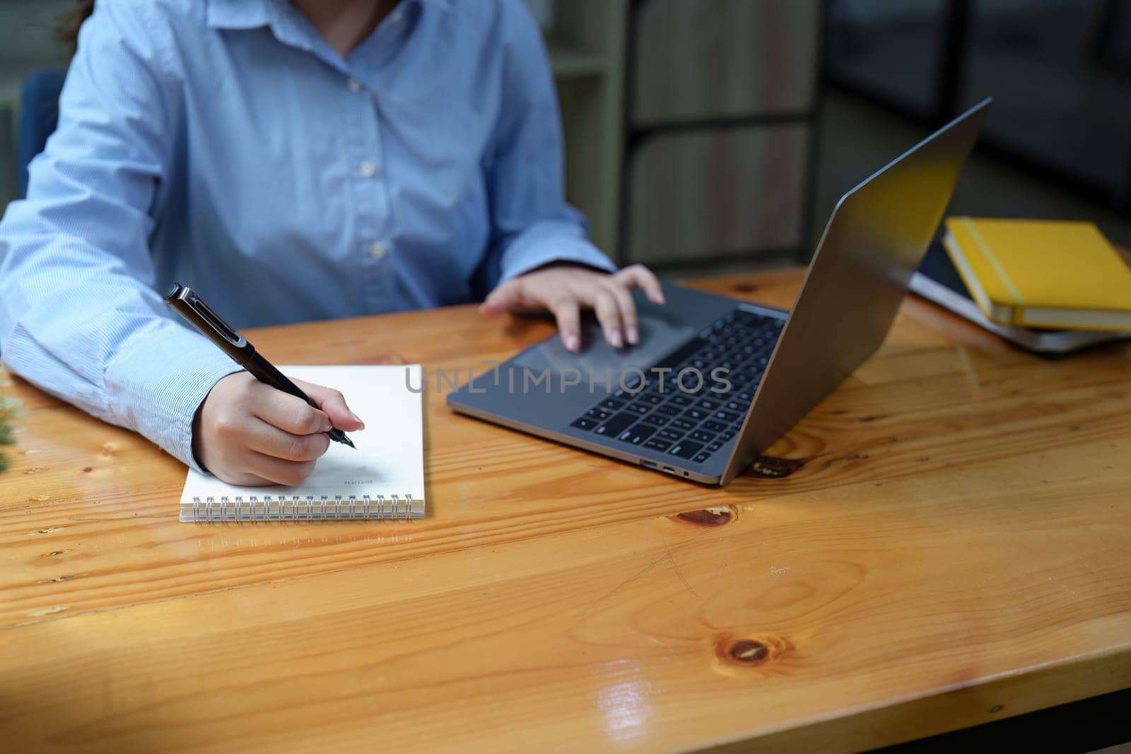 Portrait of a beautiful Asian employee working using a notebook and using a laptop computer by Manastrong