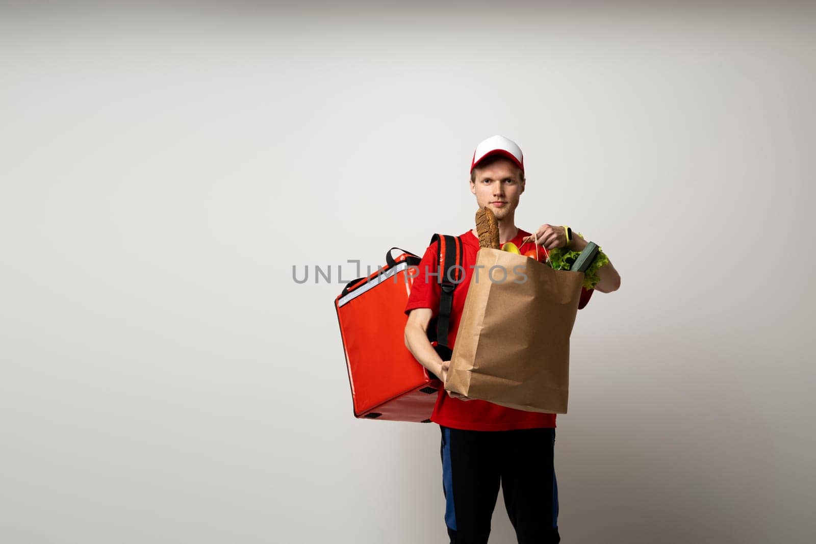 Delivery of food packages. Man with a thermal bag holding a paper bag of groceries on a white background. by vovsht