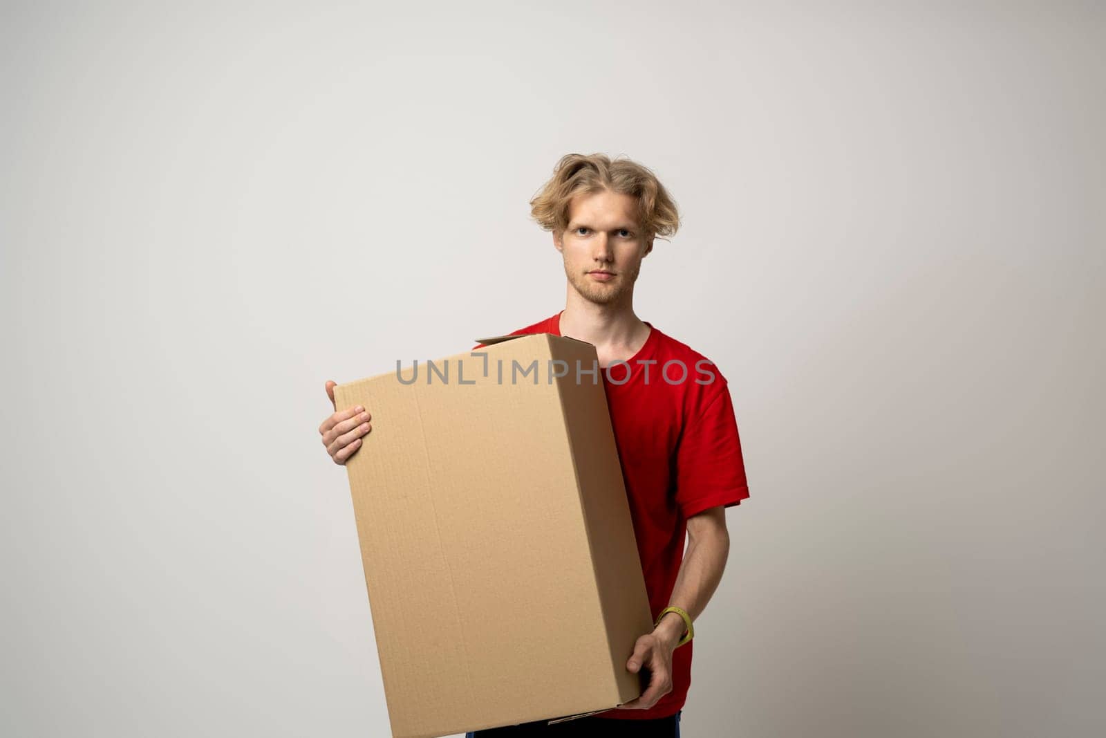 Delivery guy employee man in red uniform work as dealer courier hold blank cardboard box isolated on white background studio. Delivery service concept. by vovsht