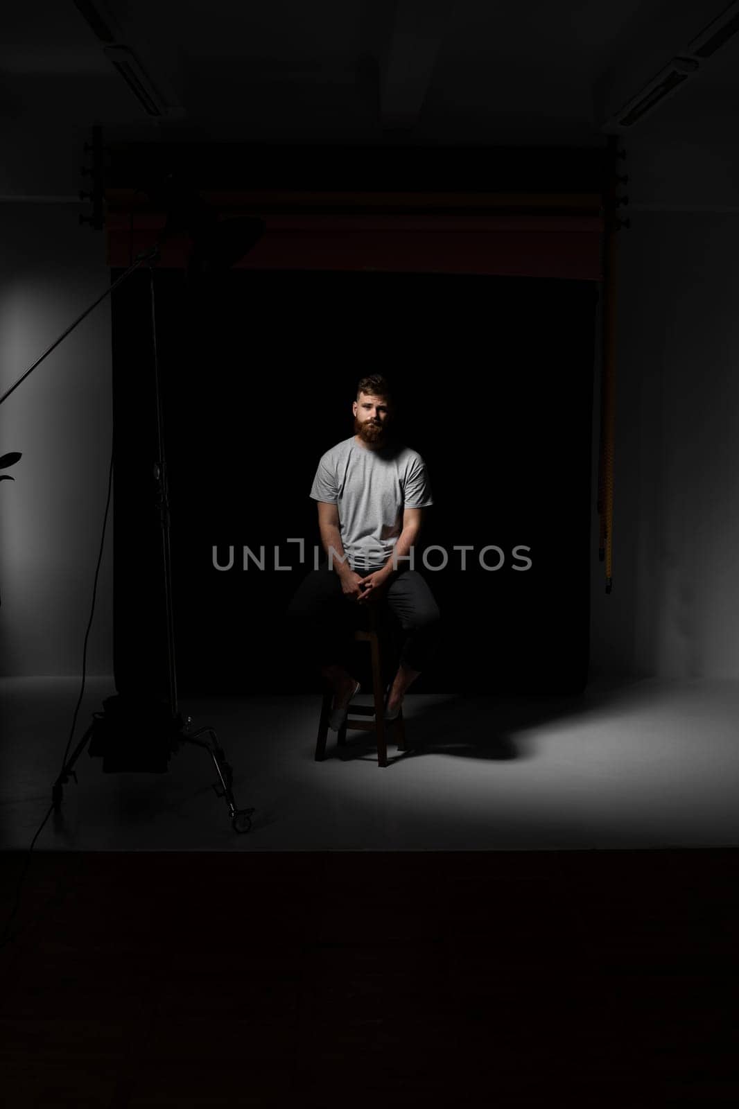 Handsome a brunette brutal bearded man in a grey t-shirt on studio photo session. Stylish and handsome man with a beard
