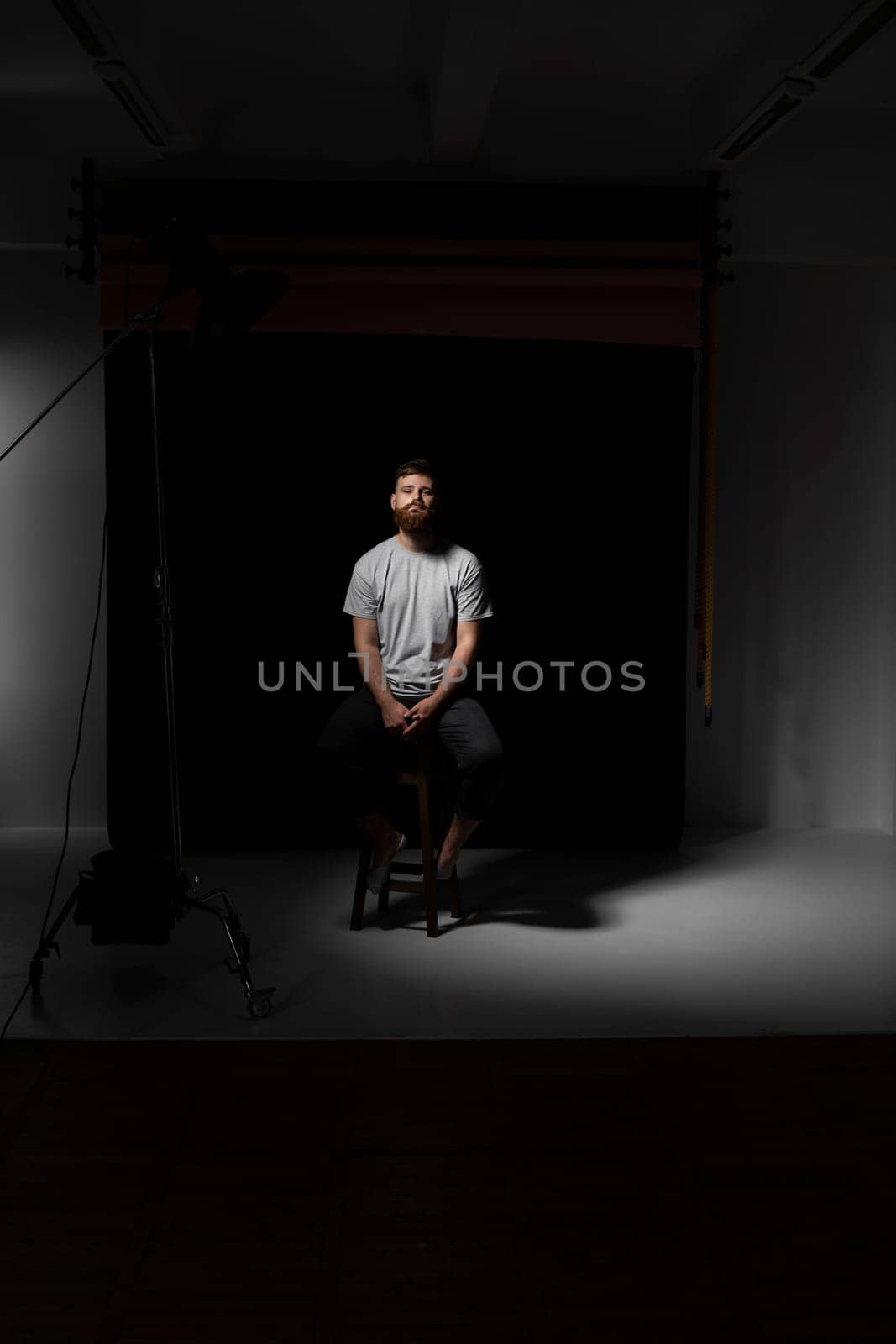 Handsome a brunette brutal bearded man in a grey t-shirt on studio photo session. Stylish and handsome man with a beard. by vovsht