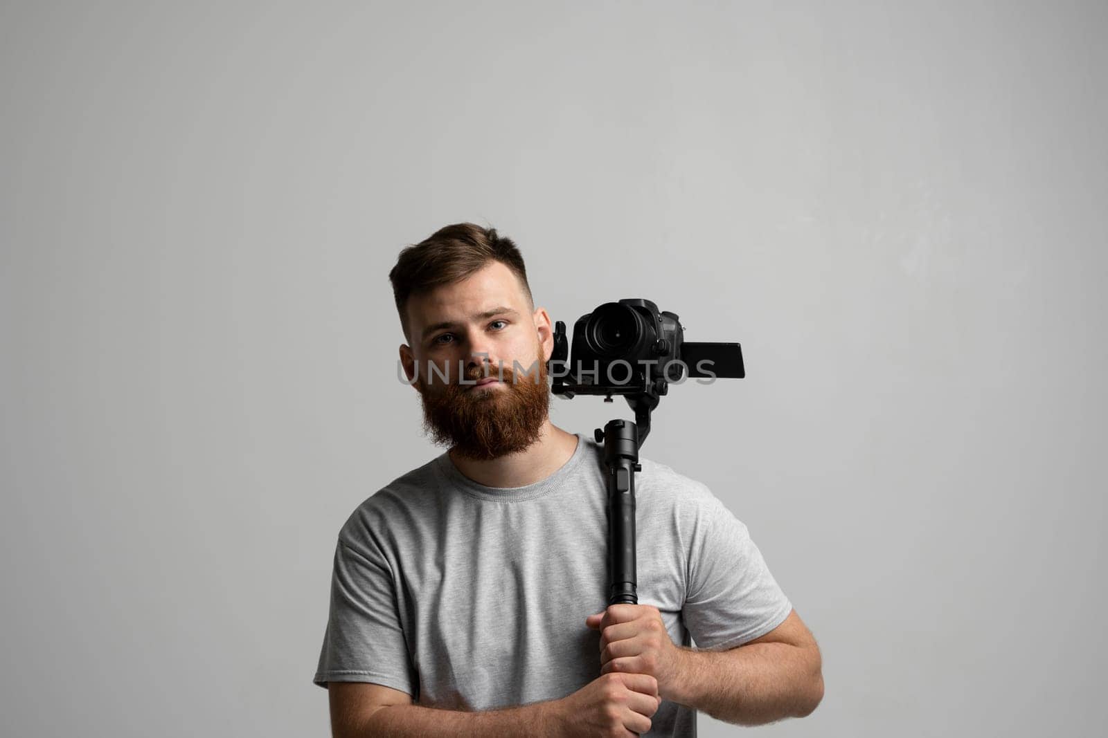 Professional bearded videographer, cinematographer, cameraman using camera on gimbal stabilizer, steadicam on white background