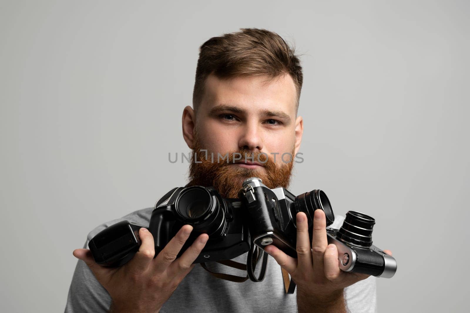 Close up portrait of man holding a old vintage film cameras. by vovsht