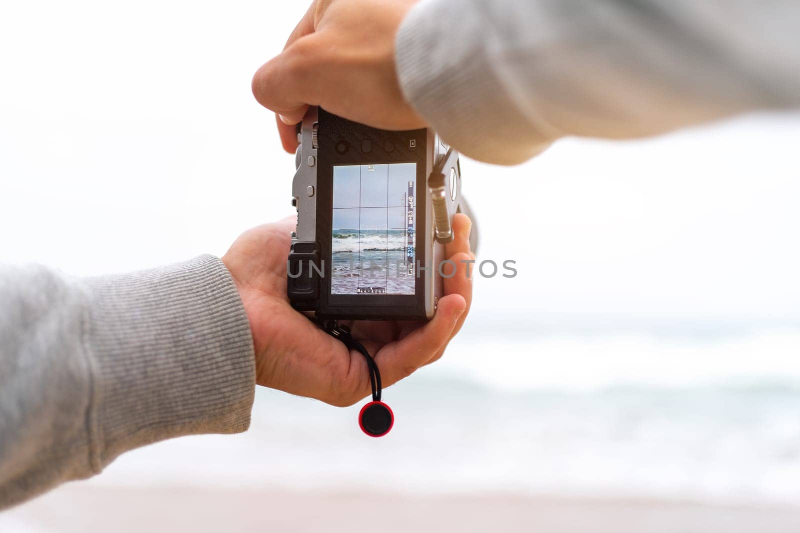 Traveller make photo using mirrorless camera in hand, travel blogger, Close up of mens hands holding mirrorless camera taking picture at ocean view