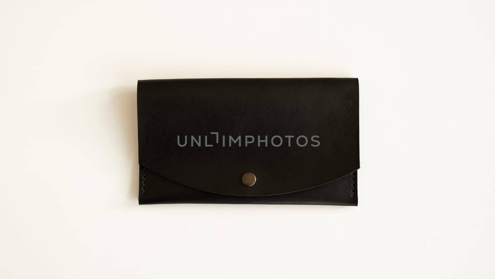 Top view of handmade brown empty man's black handmade genuine leather wallet on a button for banknotes and credit cards on white background. by vovsht