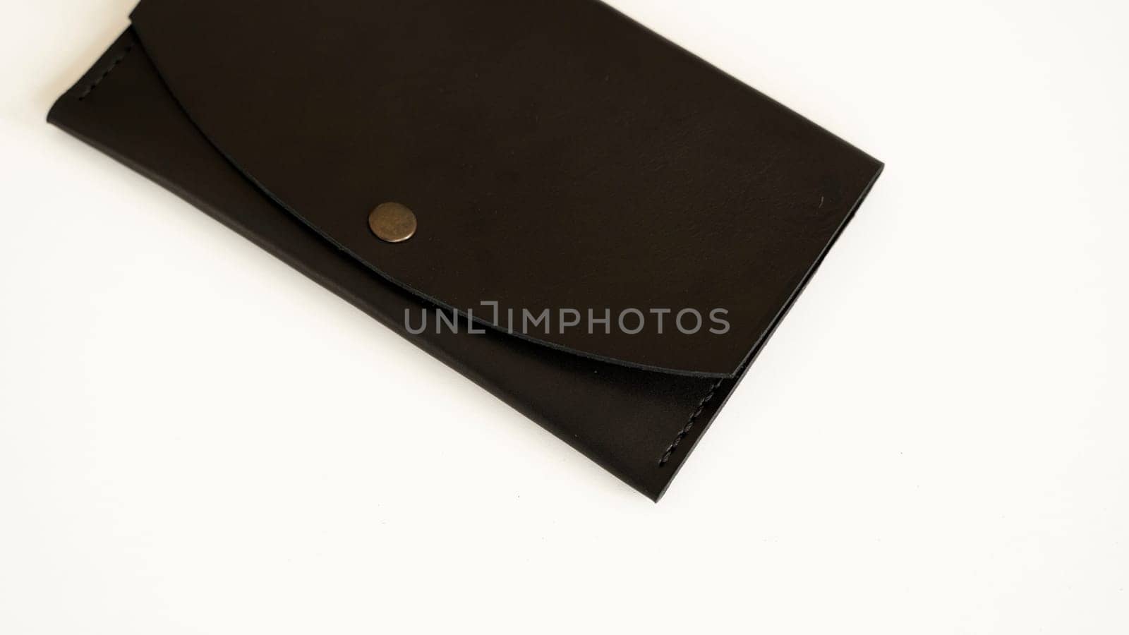 Top view of handmade brown empty man's black handmade genuine leather wallet on a button for banknotes and credit cards on white background