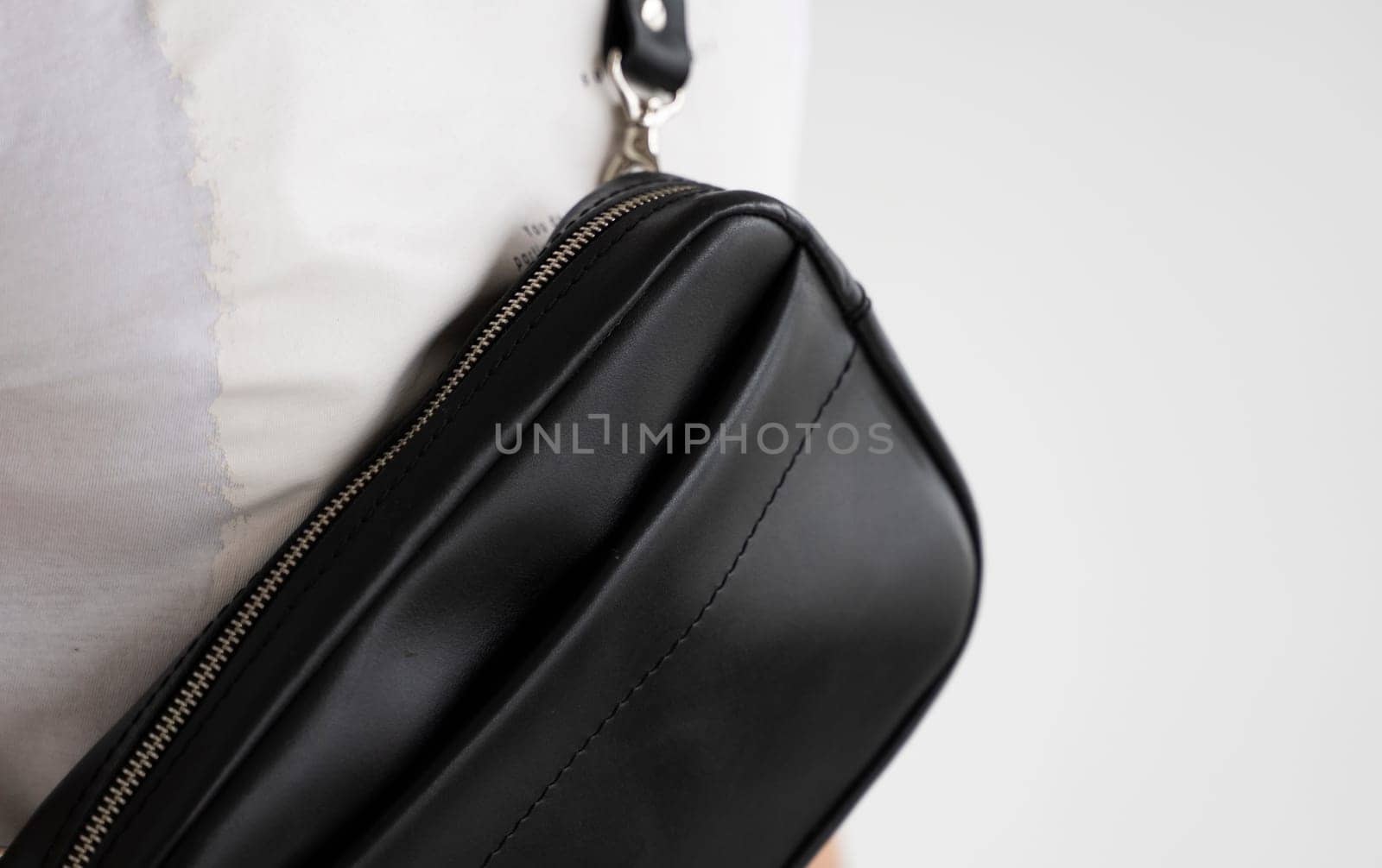 Details of leather black handmade bag over his shoulder. Dark designer banana bag. Comfortable small bag for walking