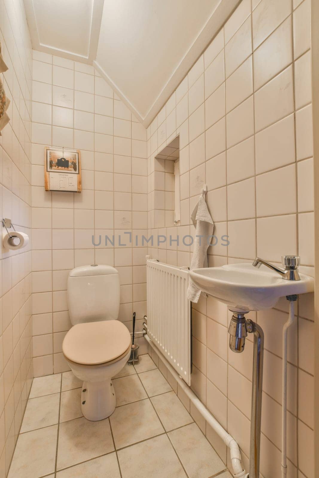 a bathroom with white tiles on the walls, and a toilet in the corner next to the sink is empty