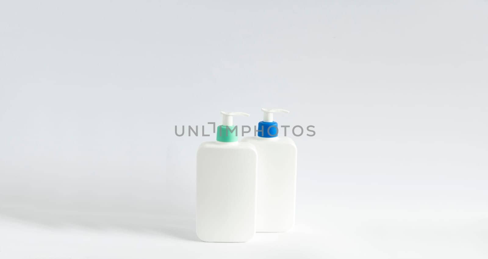 Two white unbranded bottles with a black dispenser isolated on white background. Cosmetic bottle for a cream, shampoo, oil, gel, soap, balsam