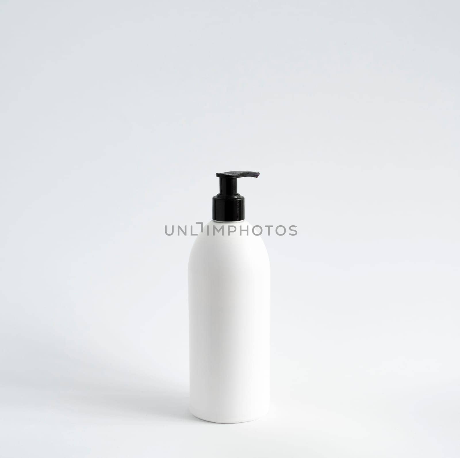 White unbranded bottle with a black dispenser isolated on white background. cosmetic packaging mockup with copy space. Bottle for a shower, gel, soap. by vovsht