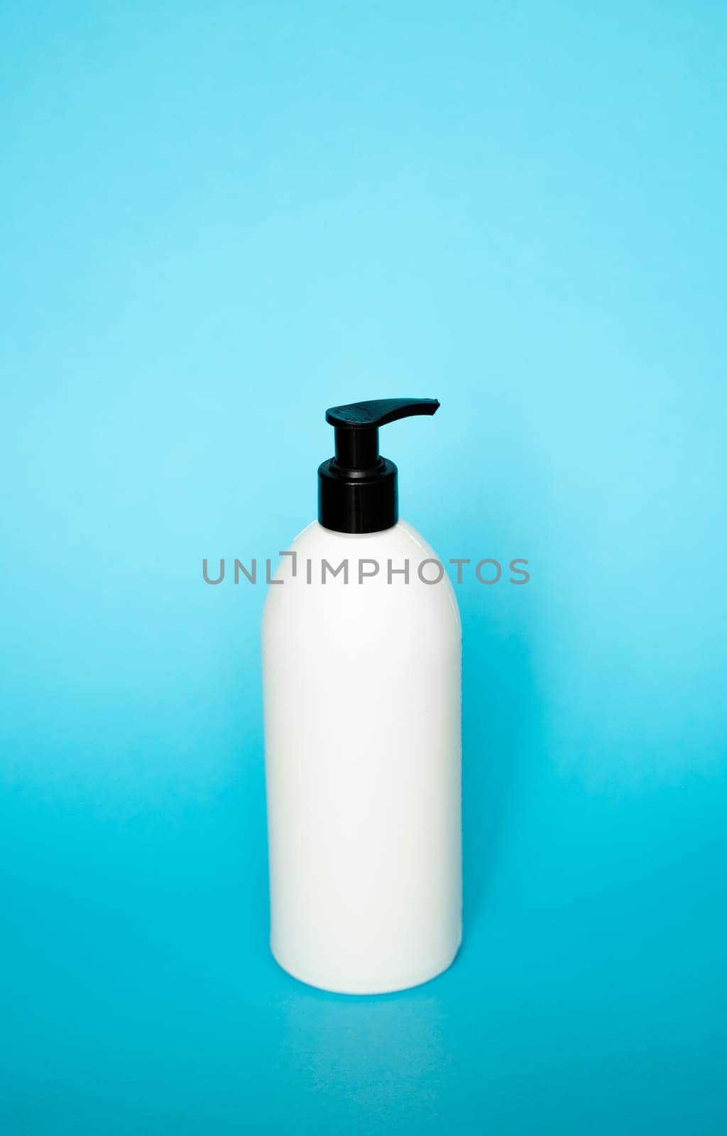 White liquid container for shampoo, gel, lotion, cream, bath foam on blue background. Blank unbranded cosmetic plastic bottle with dispenser pump