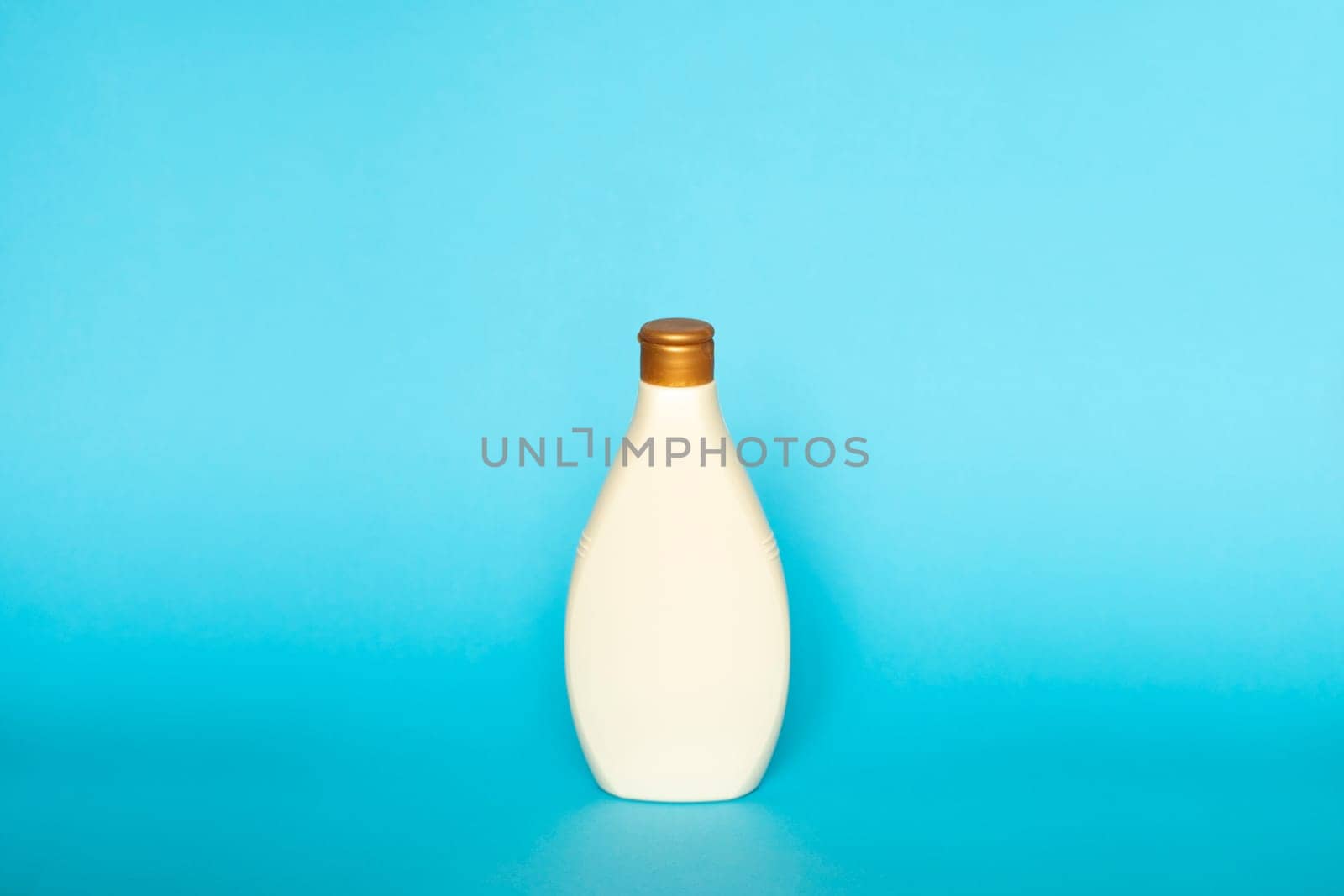 Beige liquid container for gel, lotion, cream, shampoo, bath foam. Cosmetic plastic bottle on blue background. Cosmetic packaging mockup with copy space. by vovsht