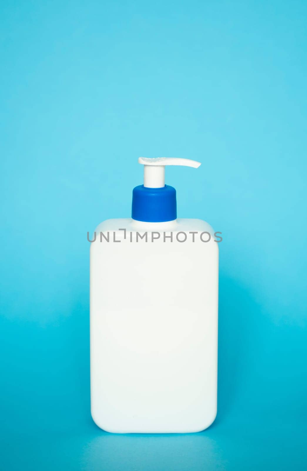 White unbranded bottle with a dispenser isolated on blue background. cosmetic packaging mockup with copy space. Bottle for a shower, gel, soap