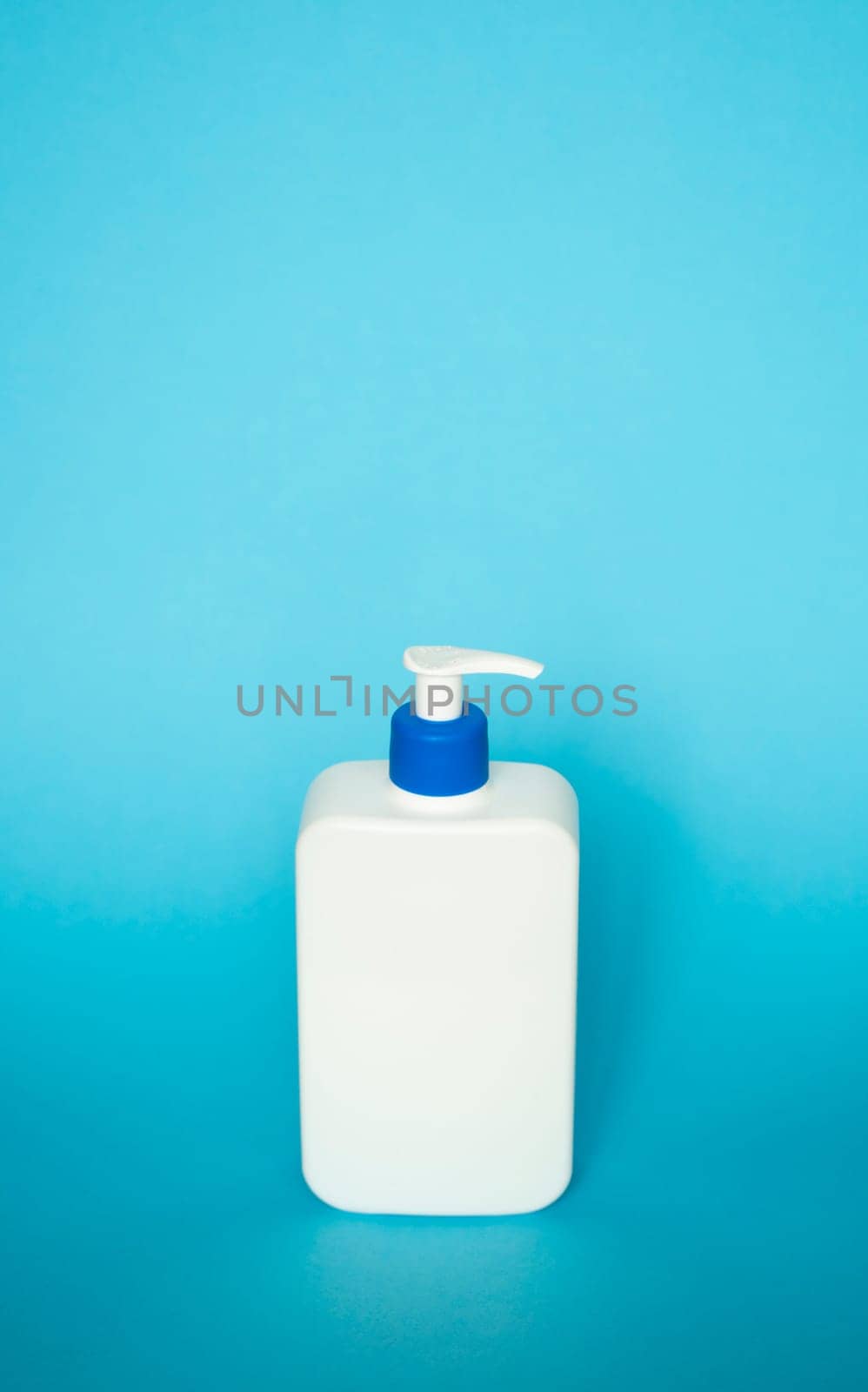 White square bottle with a blue dispenser for liquid soap, shampoo, gel on blue background. by vovsht