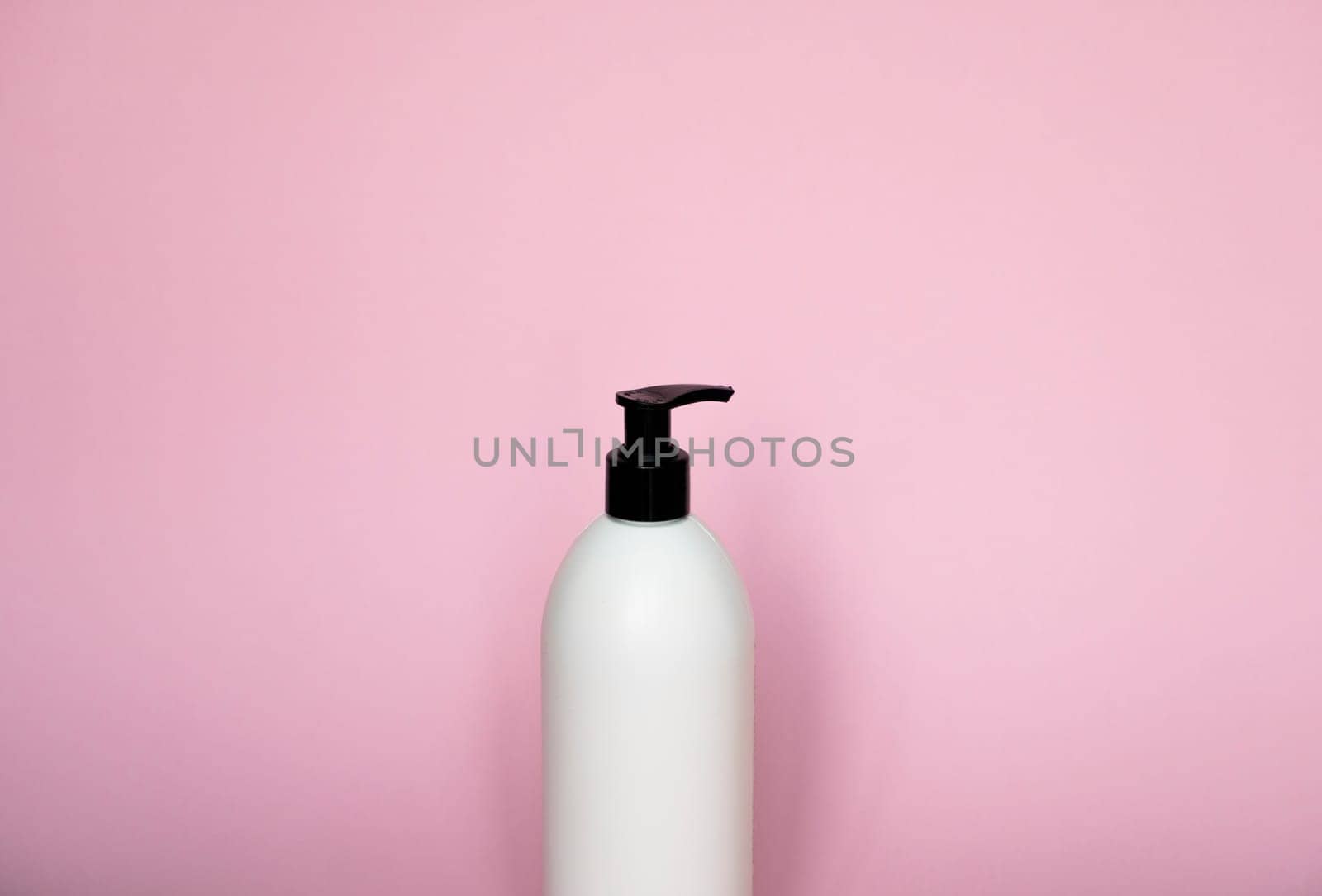 picture of white liquid container for shampoo, gel, lotion, cream, bath foam on pink background. Blank unbranded cosmetic plastic bottle with dispenser pump. by vovsht