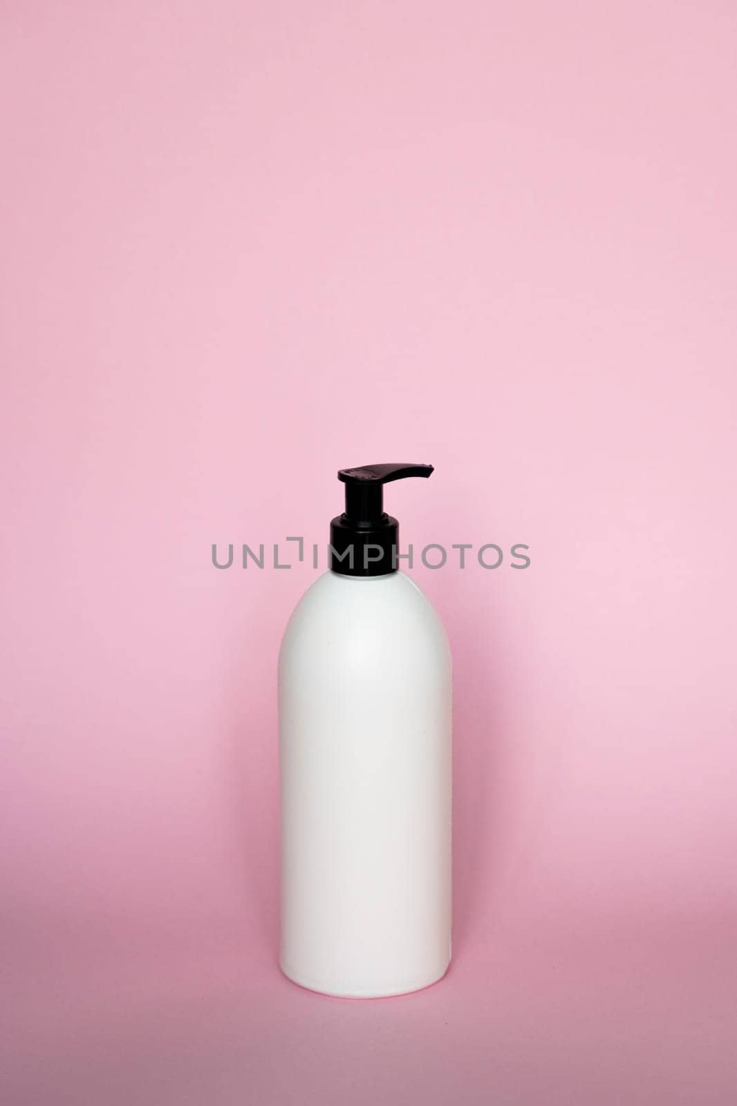 White unbranded plastic dispenser pump bottle on pink background. Cosmetic package mockup, liquid soap flacon, hand sanitizer without label, shampoo organic spa, shower gel