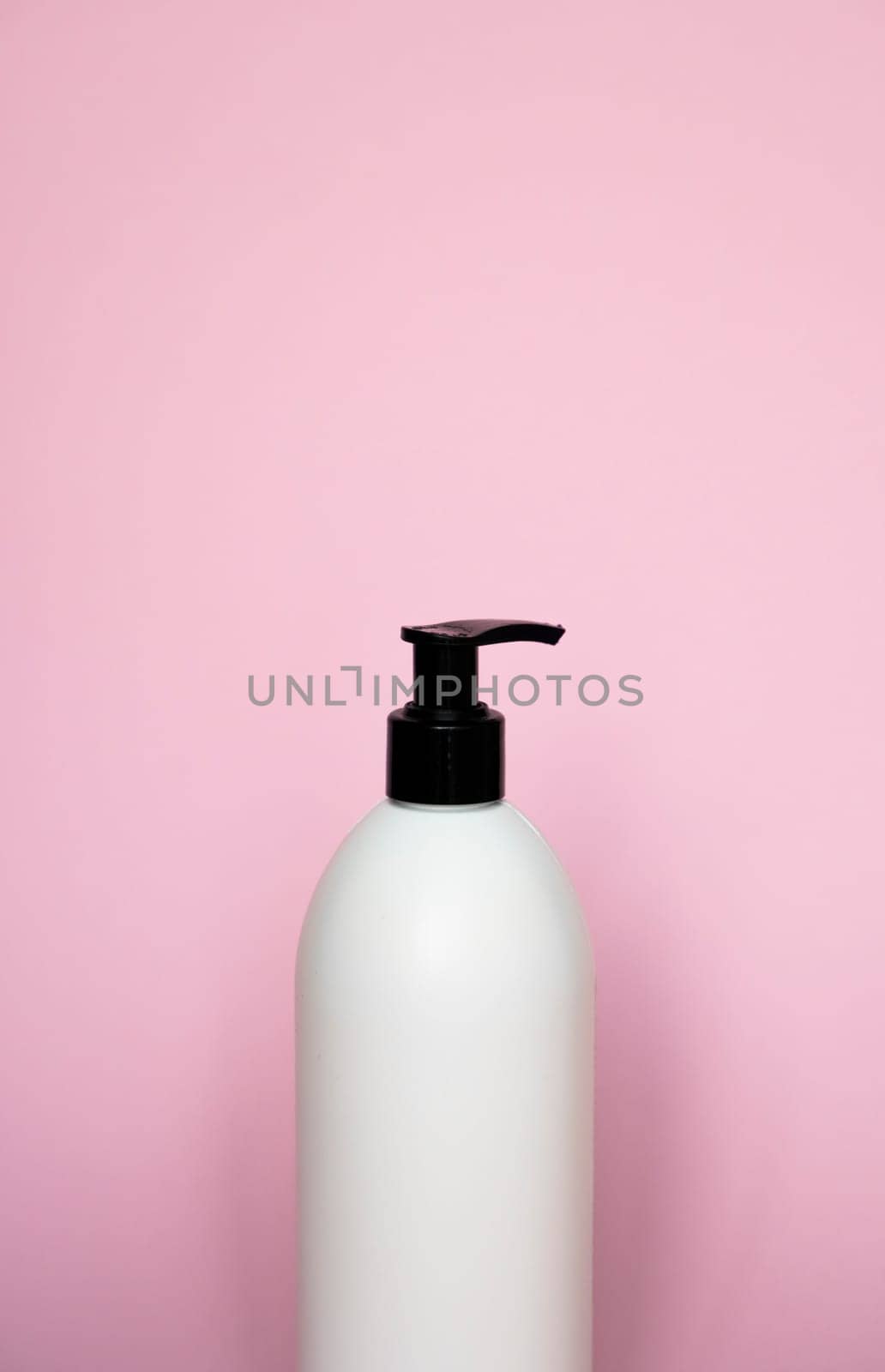 White bottle with a black dispenser for liquid soap, shampoo, gel on pink background. by vovsht