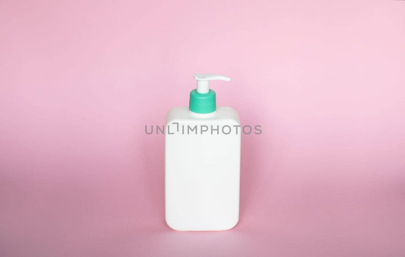 White unbranded bottle with a dispenser isolated on pink background. cosmetic packaging mockup with copy space. Bottle for a shower, gel, soap. by vovsht