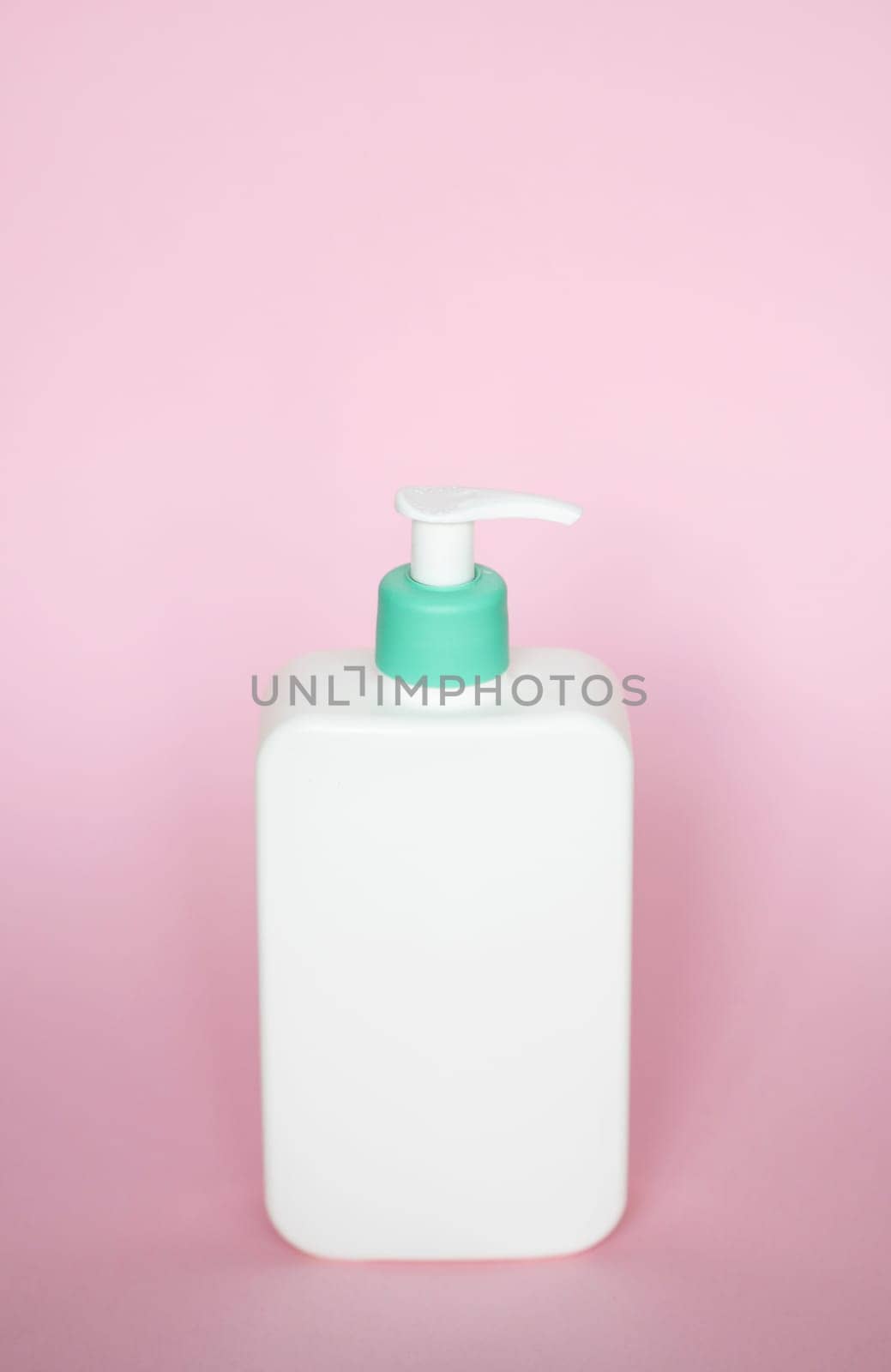 White square bottle with a cyan dispenser for liquid soap, shampoo, gel on pink background