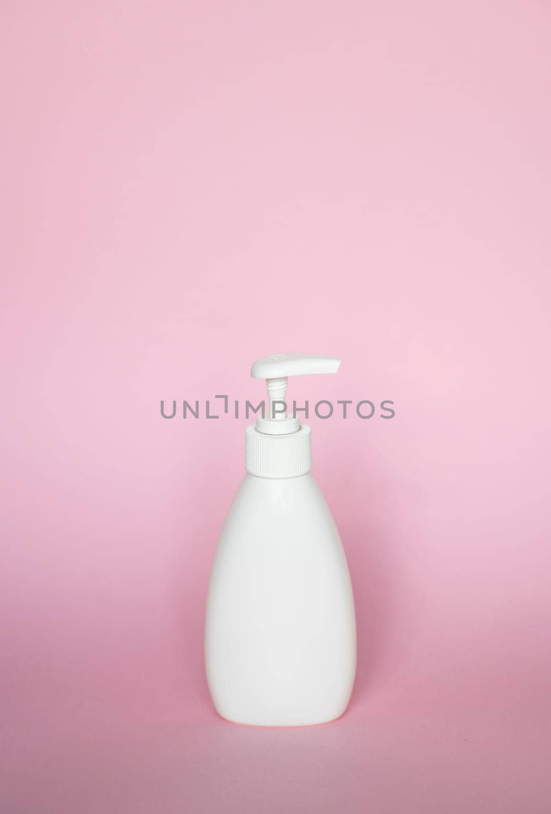 White bottle with a dispenser for liquid soap, shampoo, gel on pink background. by vovsht