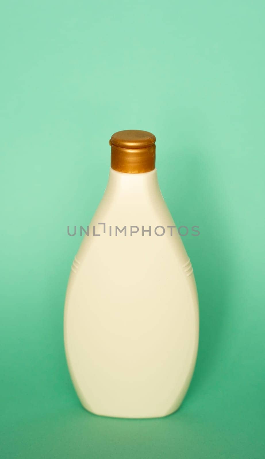 Beige container cosmetic plastic bottle for gel, lotion, cream, shampoo, bath foam on green background. Cosmetic packaging mockup with copy space. by vovsht