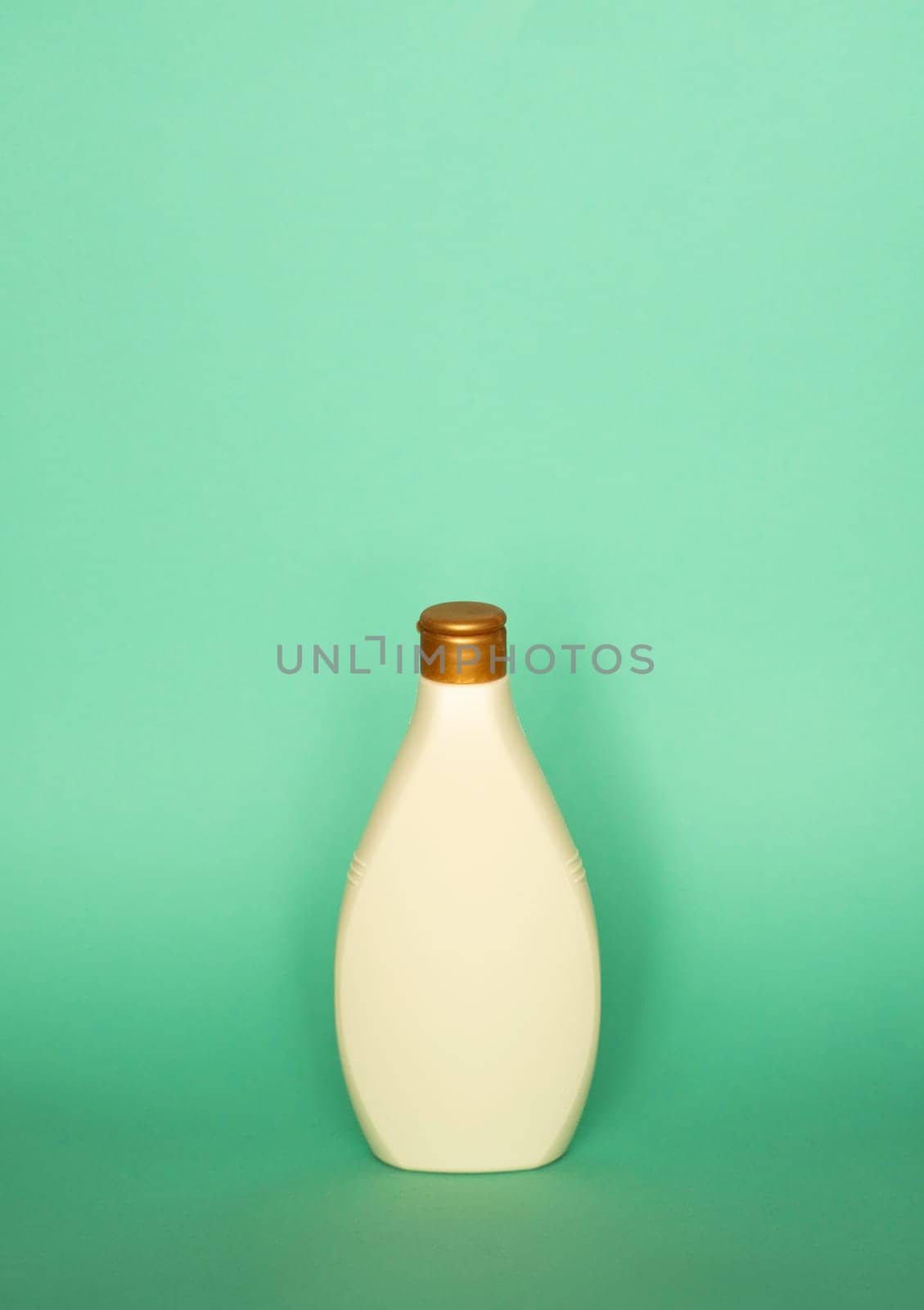 Blank beige shampoo bottle or shower gel on pastel green background. Container, beauty product and body care cosmetics
