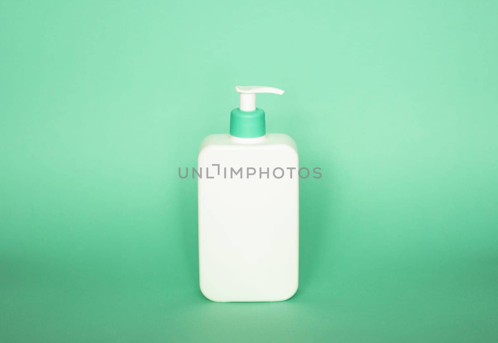 White bottle with a green dispenser for liquid soap, shampoo, gel on green background. by vovsht