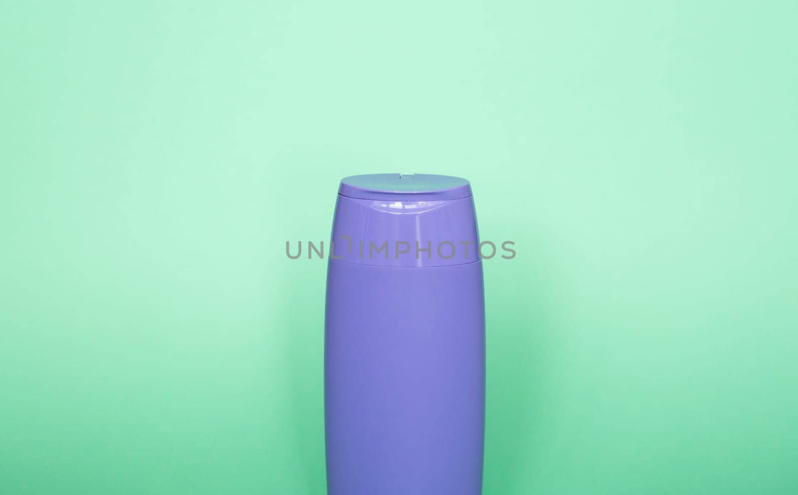 Violet blank unbranded cosmetic plastic bottle for shampoo, gel, lotion, cream, bath foam green background. by vovsht