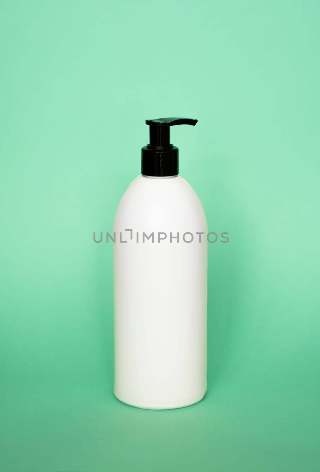 White plastic soap with black dispenser pump bottle on pastel green background. Skin care lotion, shampoo bottle, bath and body lotion. Bathroom accessories. by vovsht