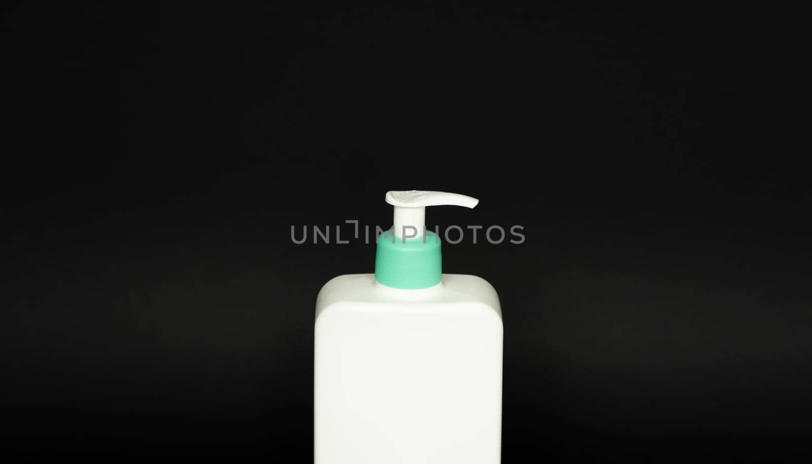 White bottle with a dispenser for liquid soap, shampoo, gel on black background