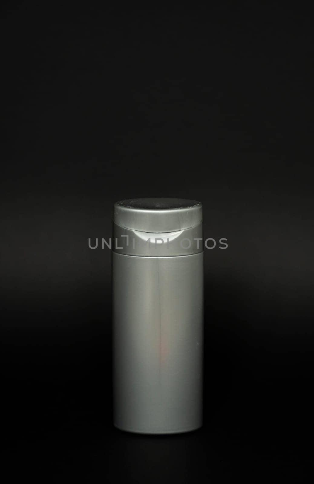 Grey liquid container for gel, lotion, cream, shampoo, bath foam. Cosmetic plastic bottle on black background. Cosmetic packaging mockup with copy space. by vovsht