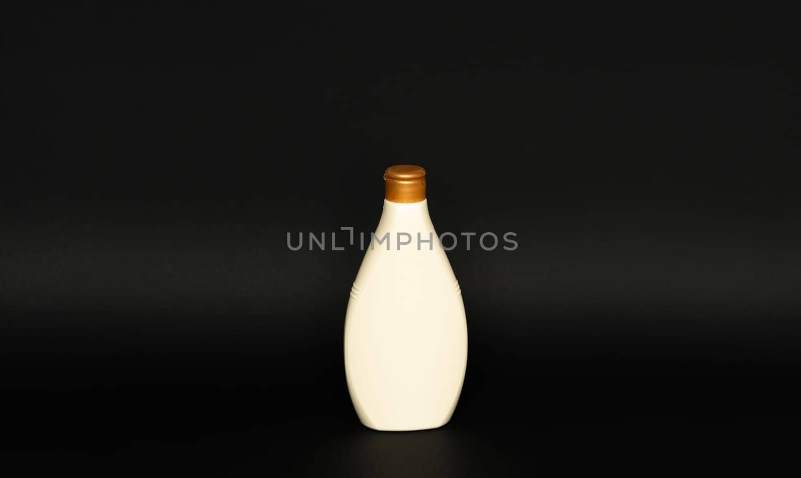 Beige cosmetic plastic bottle for gel, lotion, cream, shampoo, bath foam on black background. Cosmetic packaging mockup with copy space. by vovsht