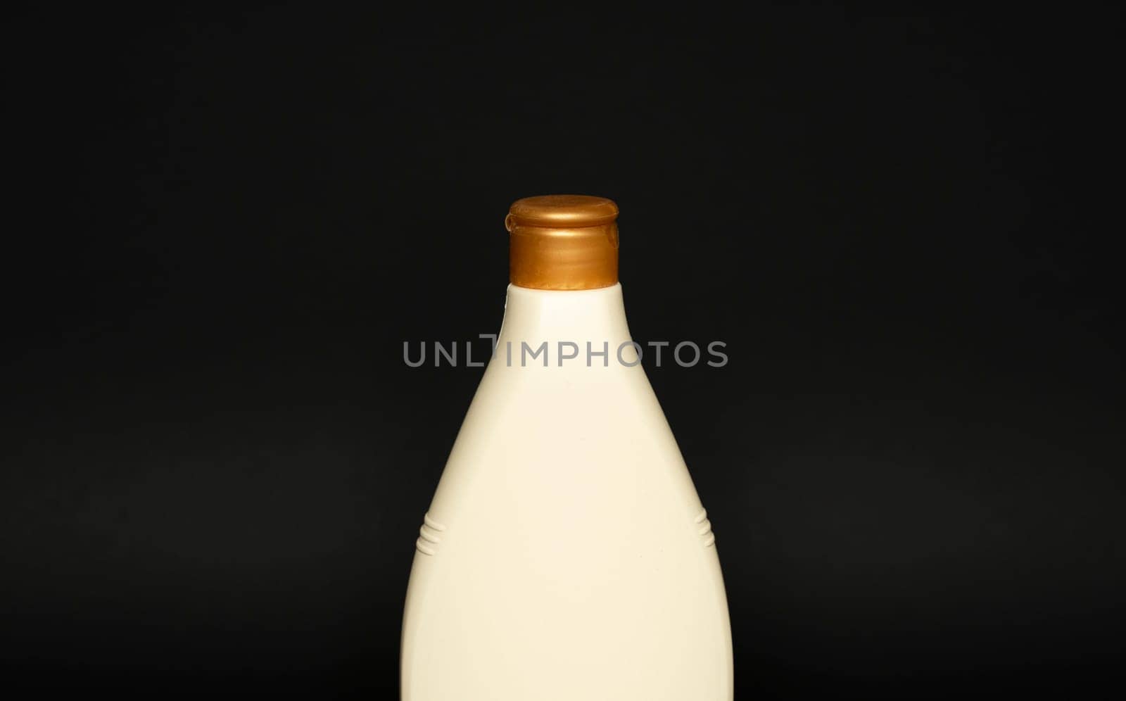 Beige cosmetic plastic bottle for gel, lotion, cream, shampoo, bath foam on black background. Cosmetic packaging mockup with copy space