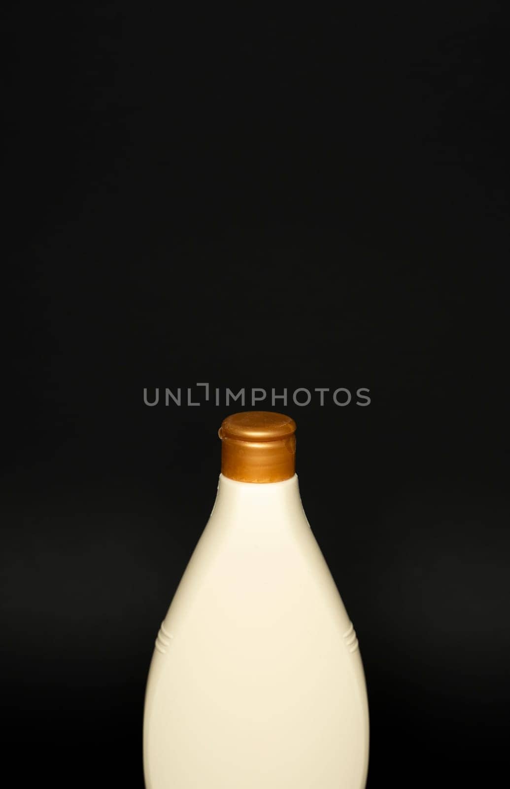 Beige cosmetic plastic bottle for gel, lotion, cream, shampoo, bath foam on black background. Cosmetic packaging mockup with copy space. by vovsht