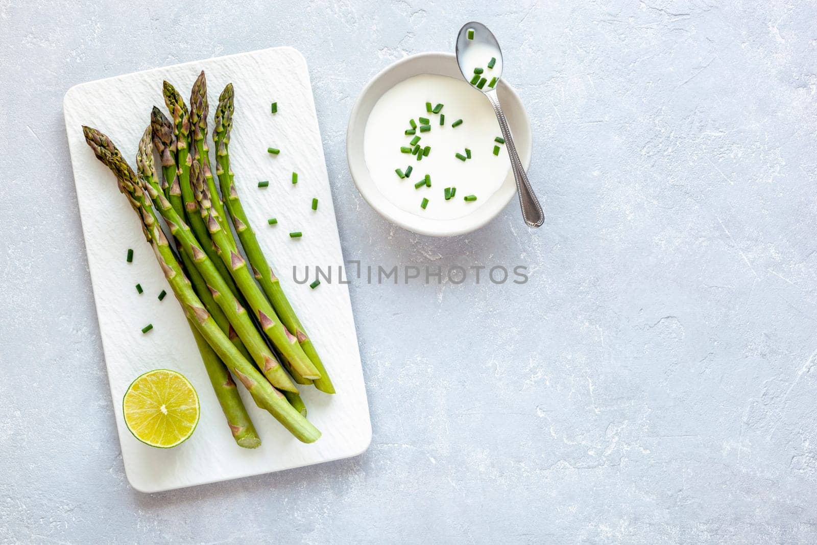 Asparagus stems on the rectangular plate served with green lemon and parsley by lanych