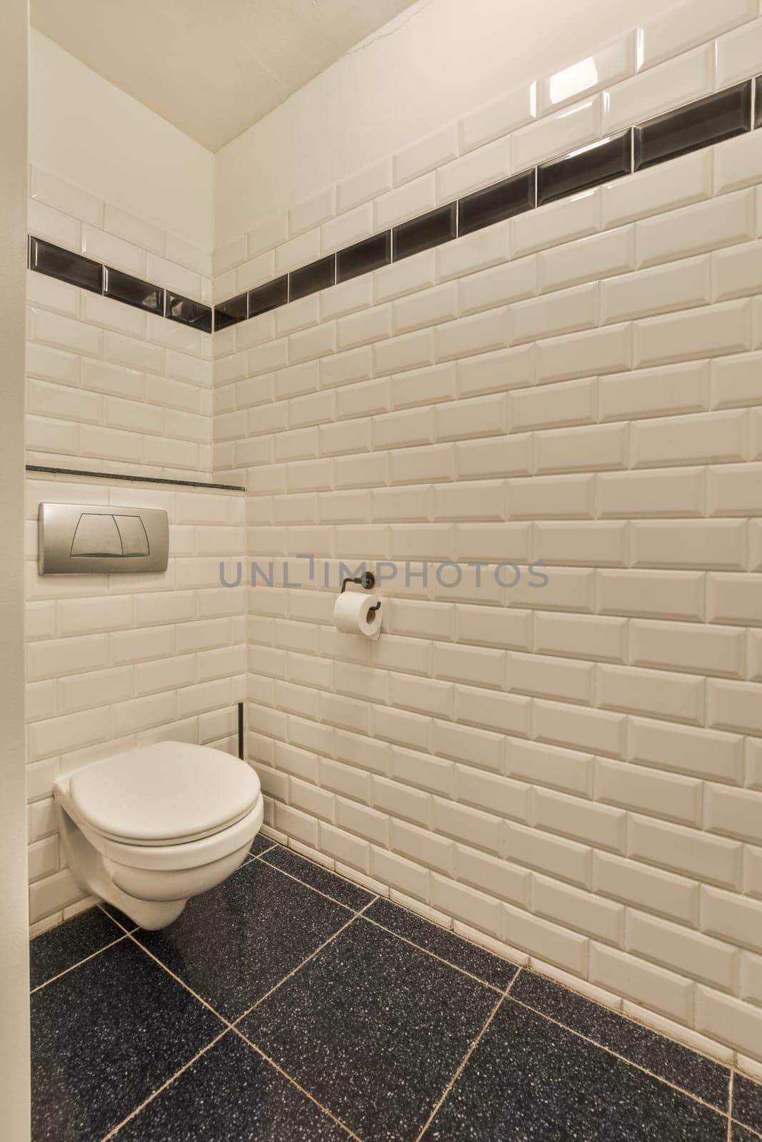 a bathroom with black and white tiles on the walls, toilet paper dispenser in the corner wall