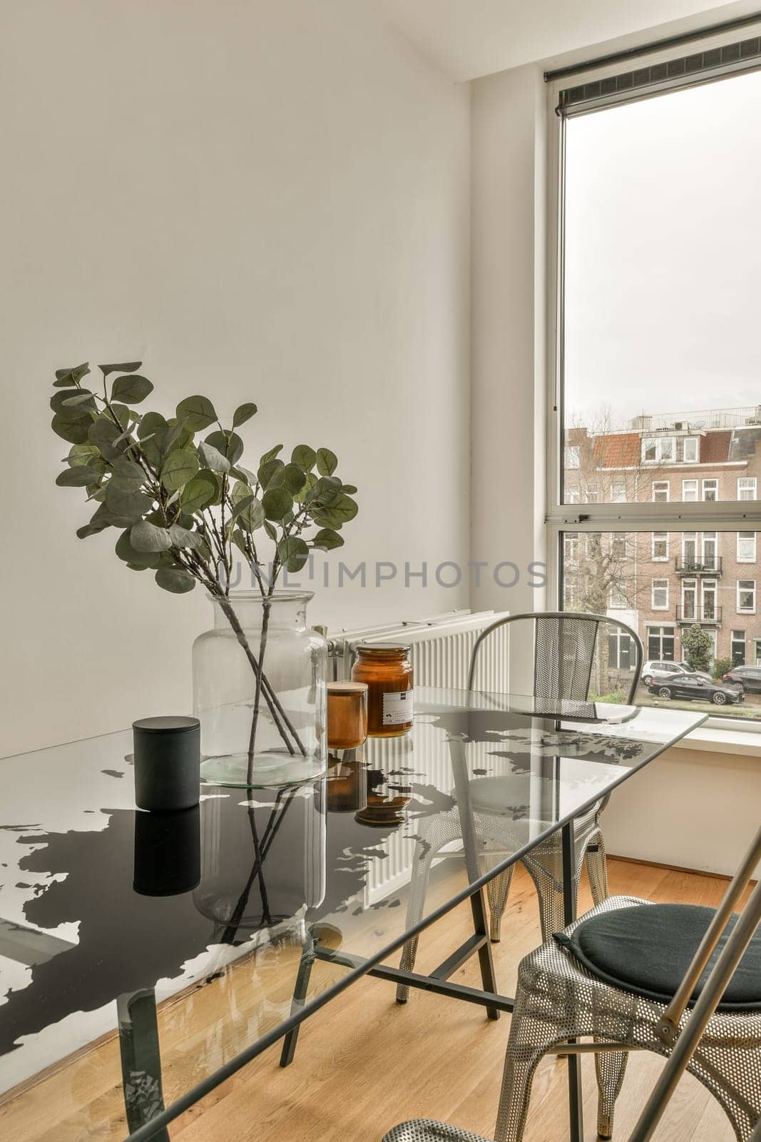 a living room with a table, chairs and a plant on the floor in front of a large glass window