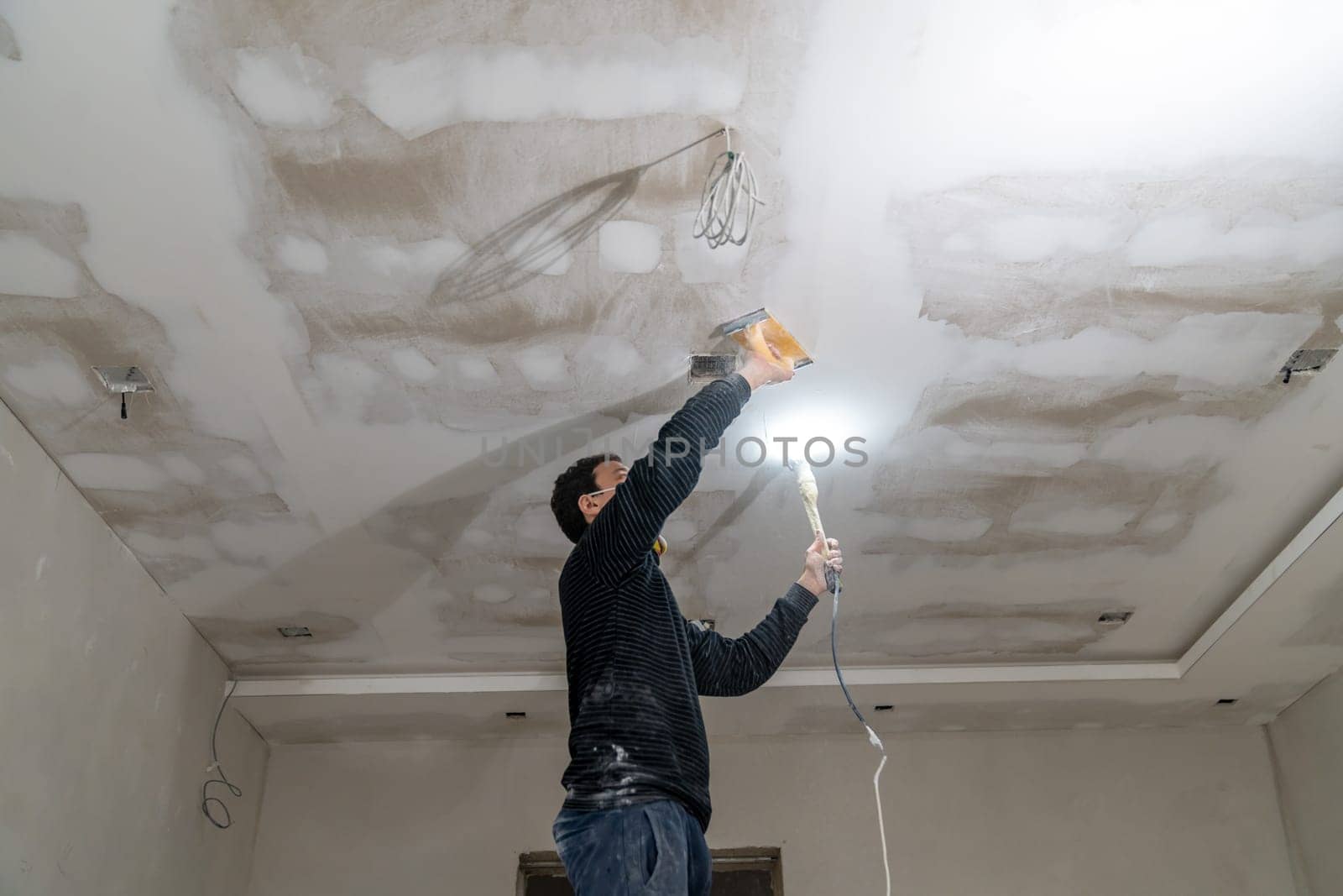 hand sanding of the plasterboard ceiling with a trowel.