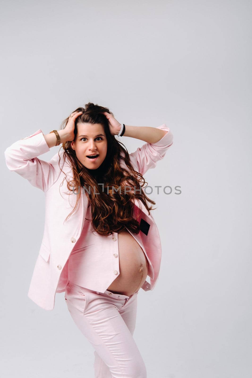 pregnant woman in pink suit close-up on gray background.