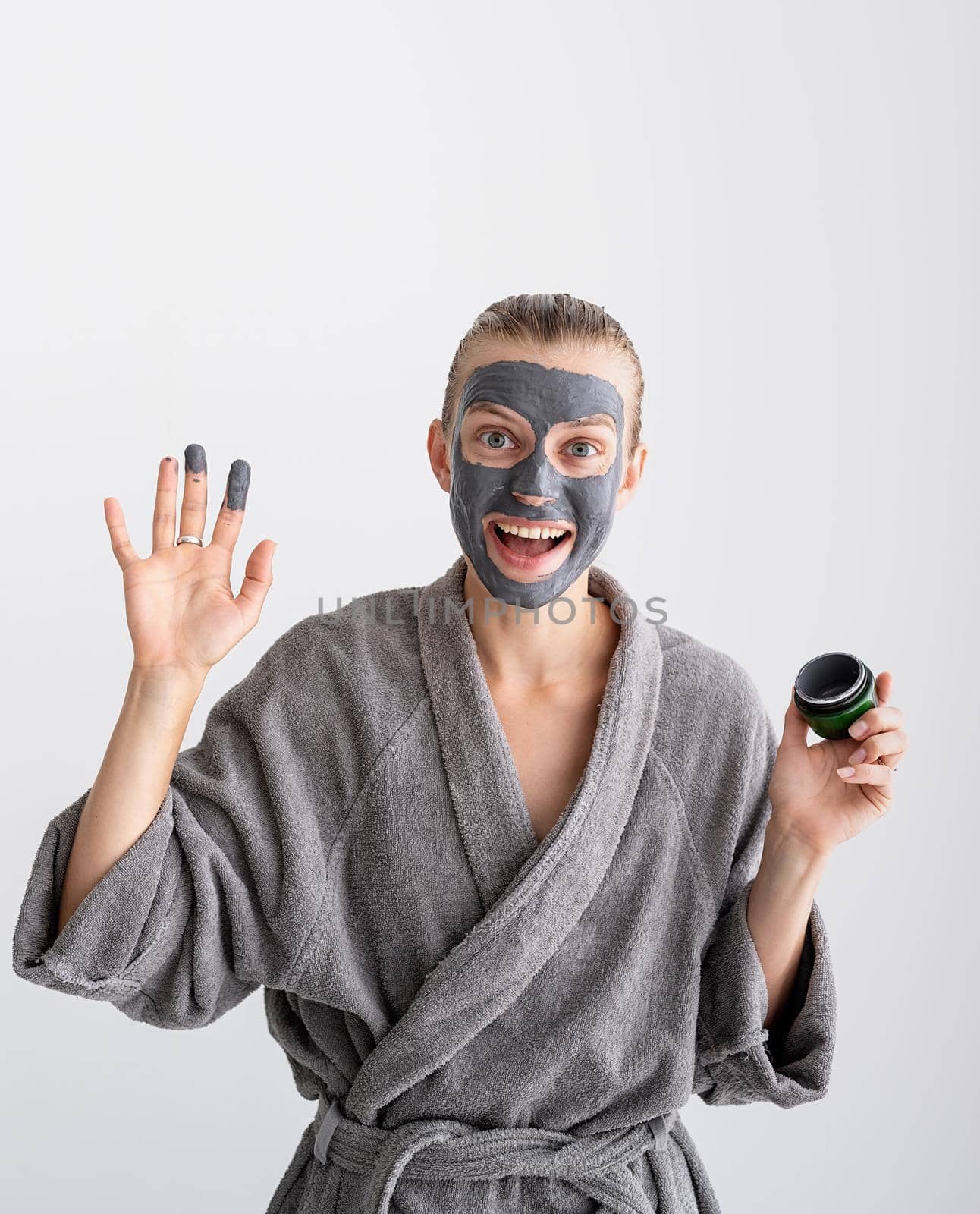 Womens health. Spa and wellness. Happy woman applying face mask waving hello
