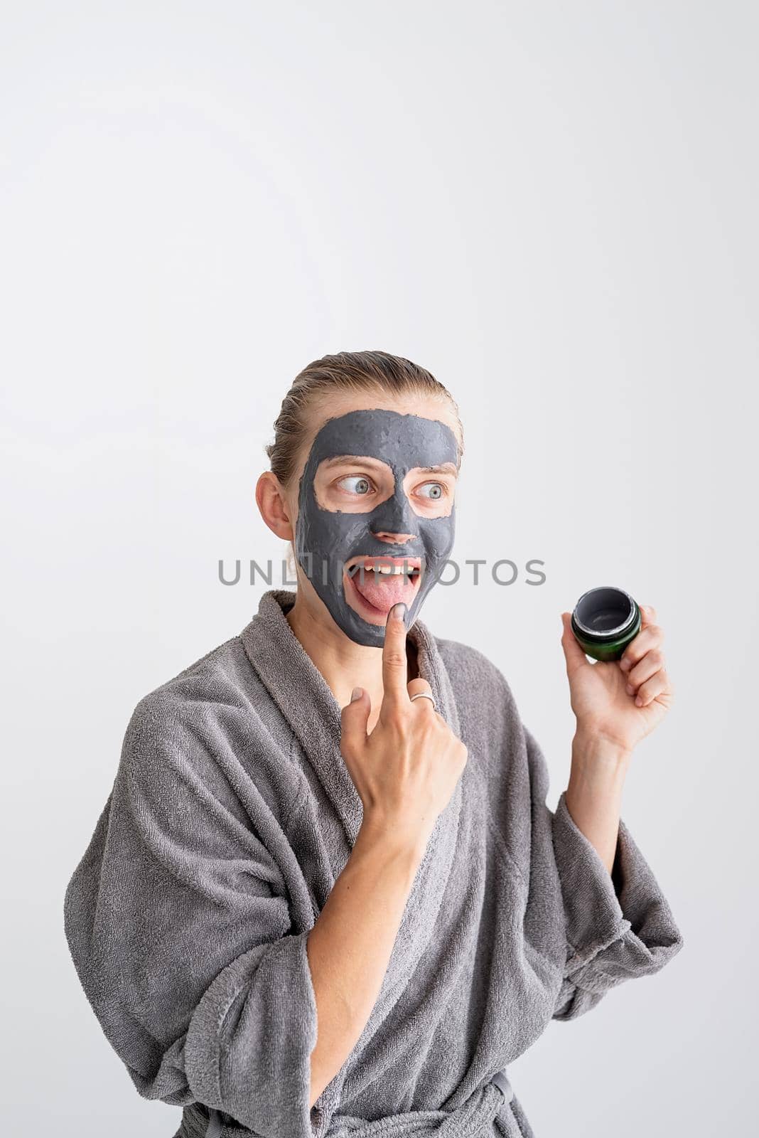 Womens health. Spa and wellness. Happy funny woman applying face mask and tasting it