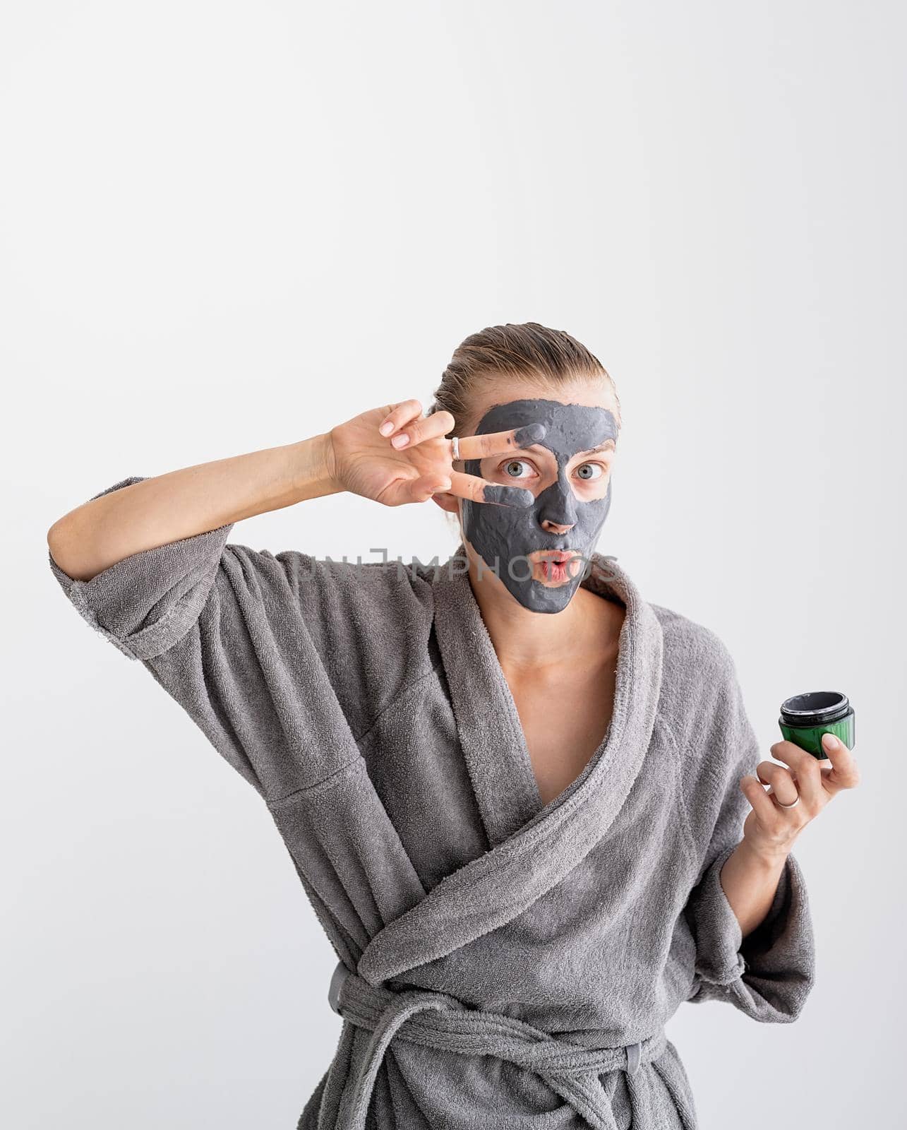 Womens health. Spa and wellness. Happy funny woman applying face mask waving hello