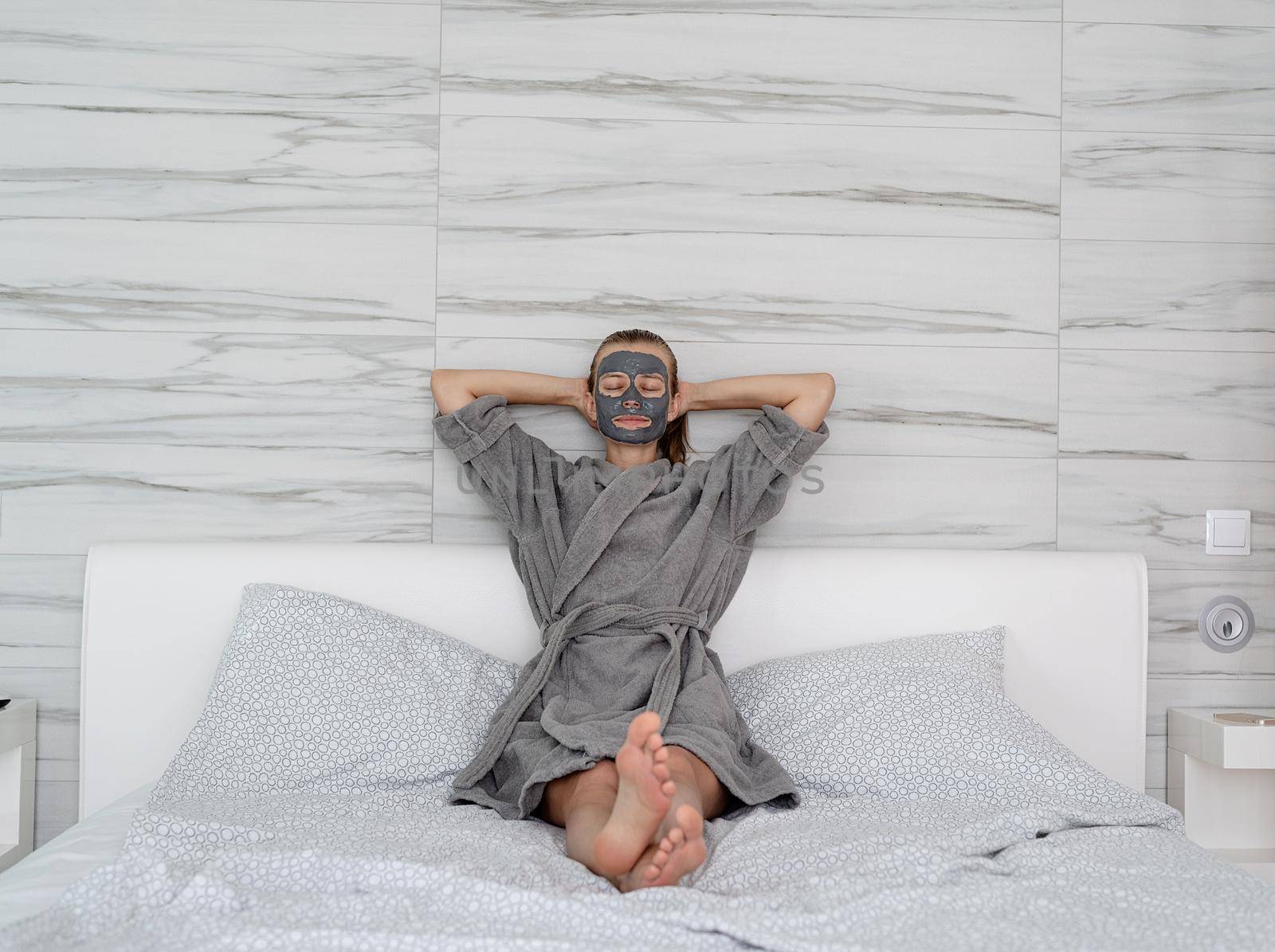 Womens health. Spa and wellness. Woman with face mask relaxing sitting on the bed