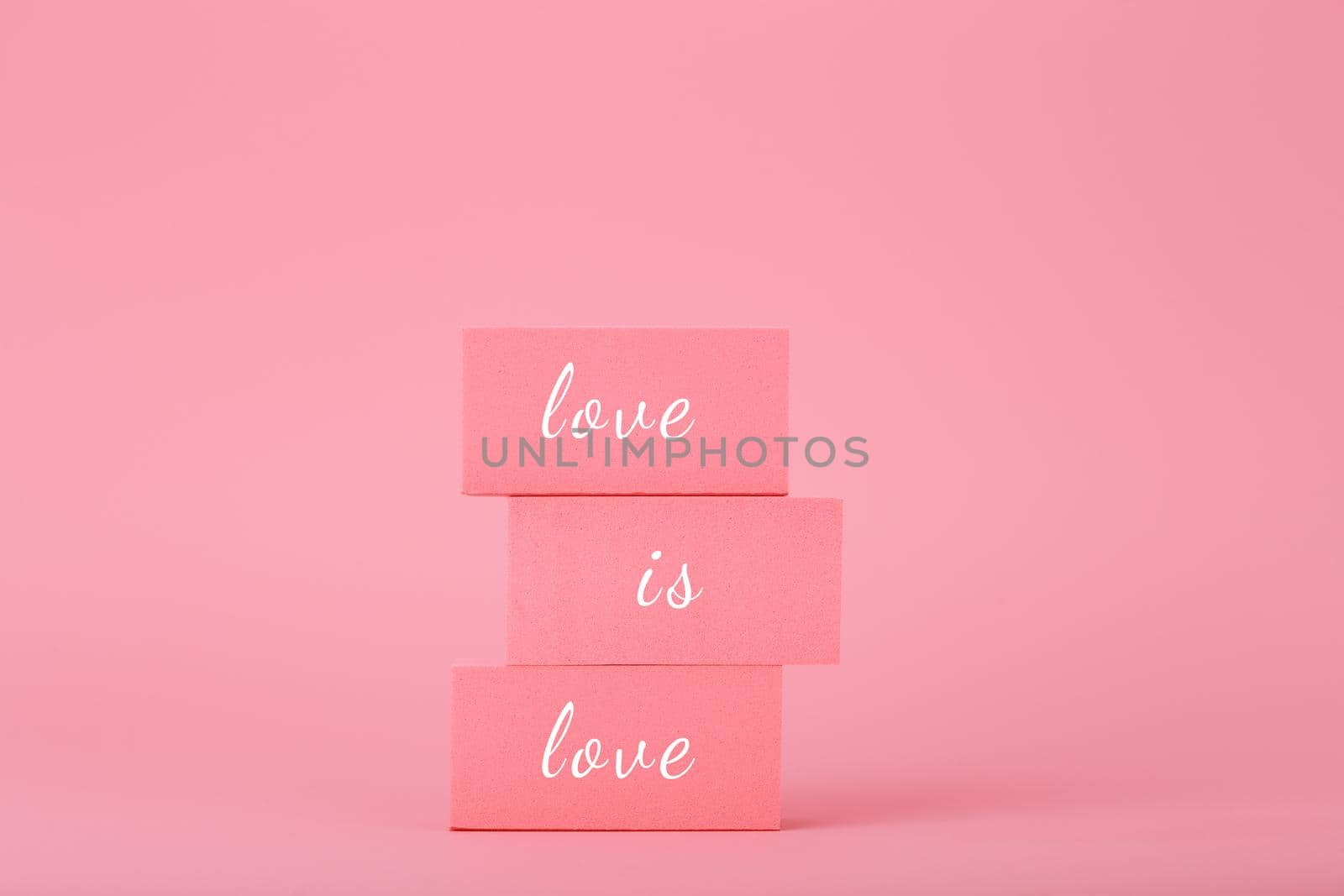 Love is love elegant concept in bright pink colors. Love is love written on pink rectangular blocks against pink background. Concept of Lgbtq pride social post, tolerance, respect and equal rights