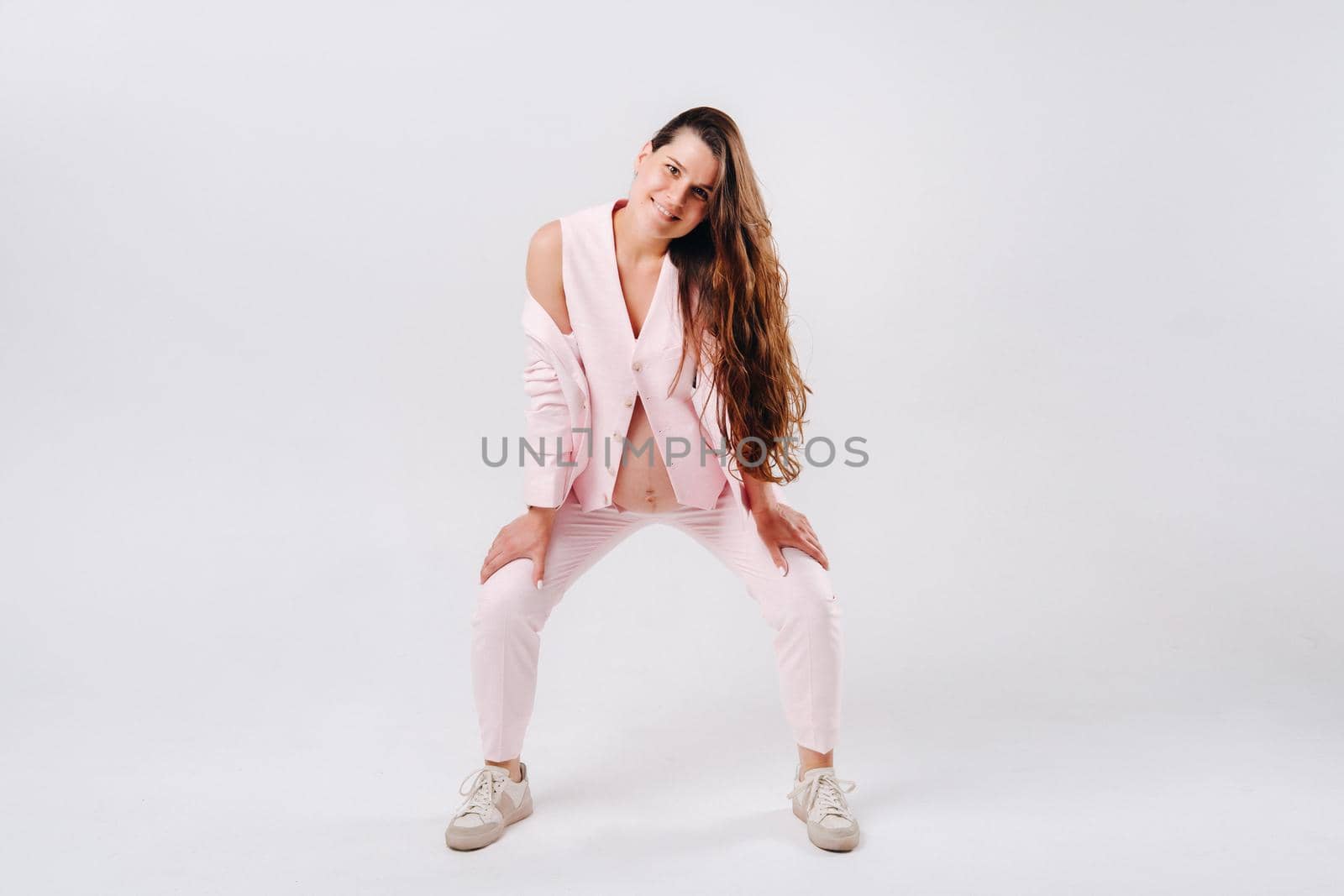 pregnant woman in pink suit close-up on gray background.