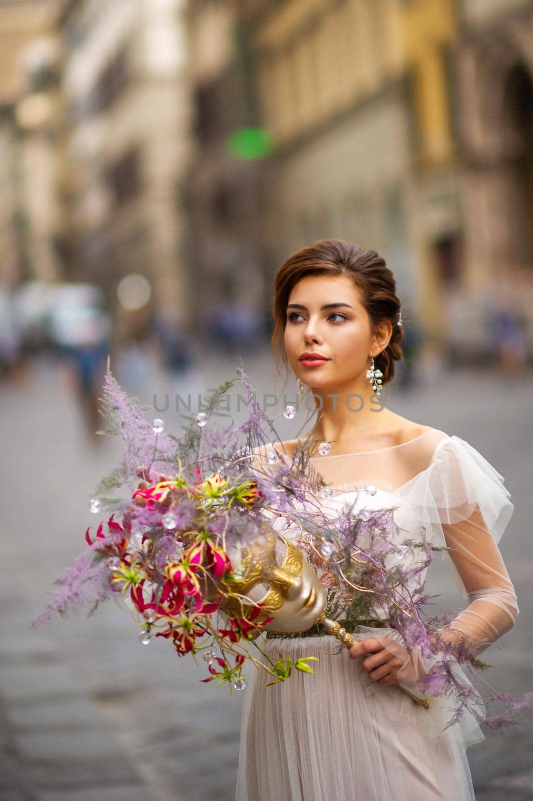 a bride in a wedding dress with a Venetian mask in her hands in Florence.Italy by Lobachad