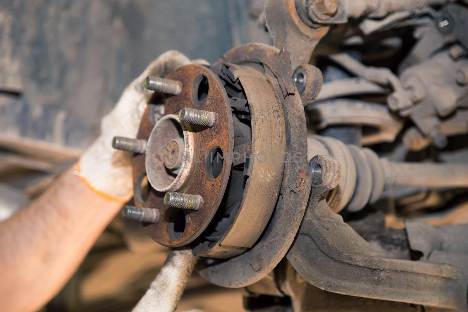 The man's hands remove the worn and rusted brake pads from the rear wheel. In the garage, a person changes the failed parts on the vehicle. Small business concept, car repair and maintenance service.