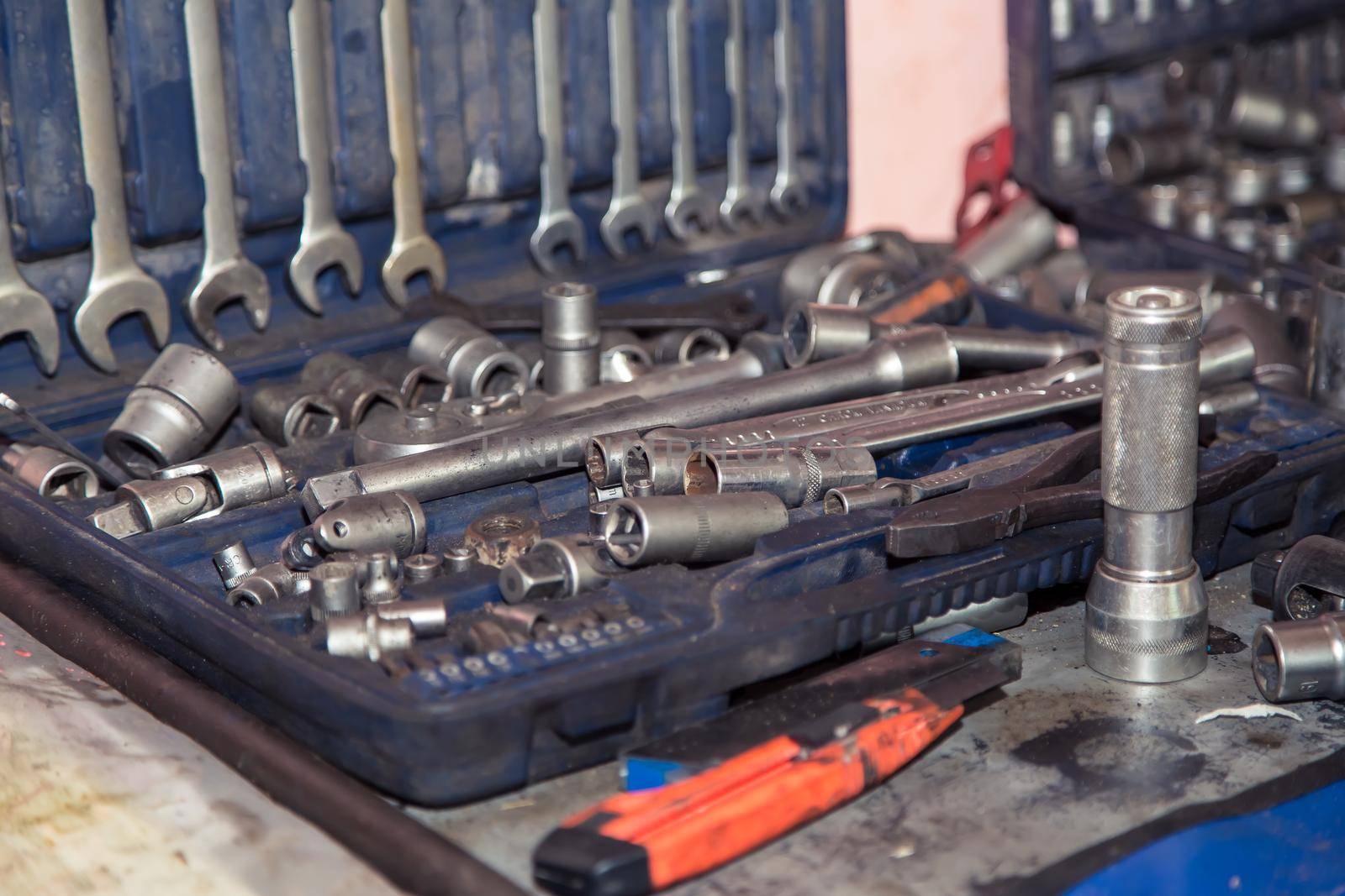 A set of wrenches in a case on a metal workbench in the workshop. In the garage are tools for repairing broken vehicle parts. Small business concept, car repair and maintenance service.